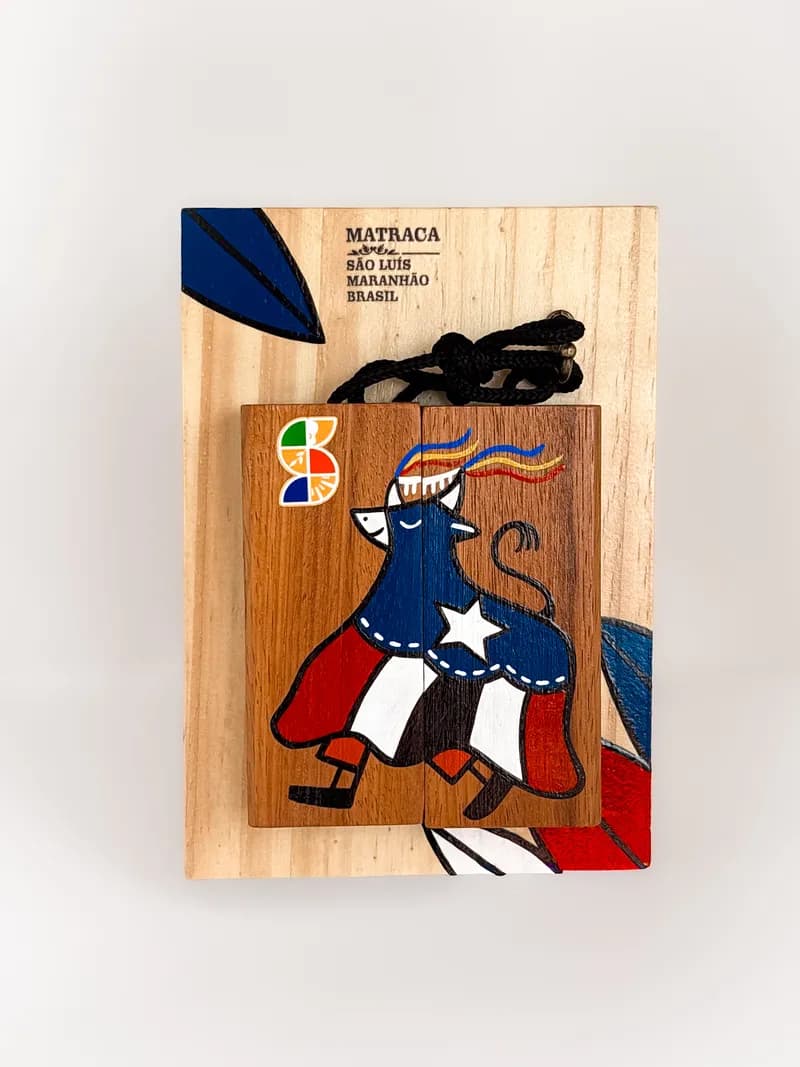 Matraca de madeira pintada à mão com a figura do boi em vermelho, branco e azul