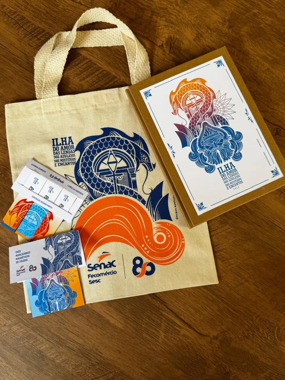 Ecobag e caderno personalizados com a arte Ilha do Amor e a marca Senac Fecomércio Sesc 80 anos